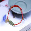 Natural jade bead bracelet with gold tone lotus seed charm on red string