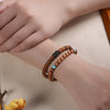 Two wooden bracelets wrapped around a wrist, featuring brown disc beads and round beads with turquoise accents.
