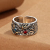 Close up of a wide copper ring with a dragon pattern and red and blue stones