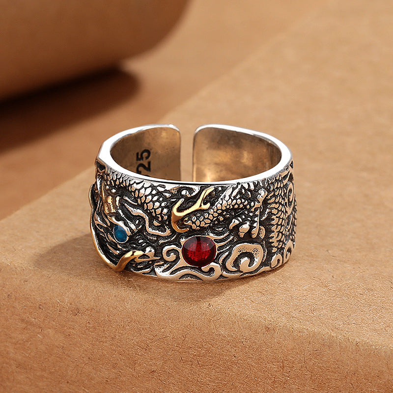 Close up of a wide copper ring with a dragon pattern and red and blue stones