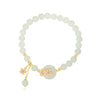 Close up of a white jade beaded bracelet with pink flower charms on a wrist