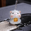 A cute resin cat tea pet changing color from white to yellow as hot water is poured over it