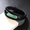 Close up of a black braided leather bracelet with a green stone center