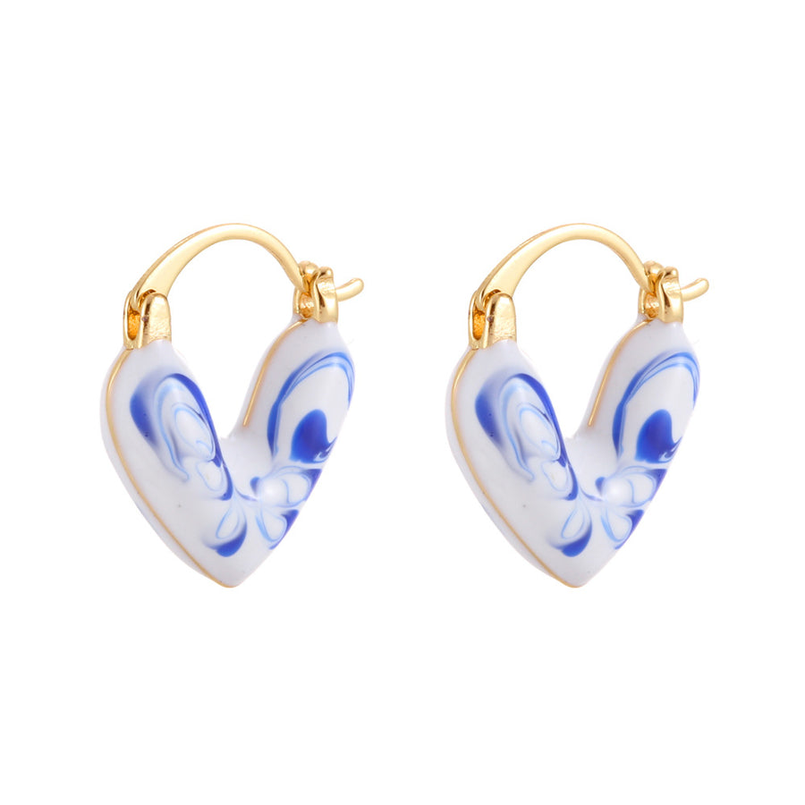 Close up of blue and white porcelain heart shaped hoop earring on ear