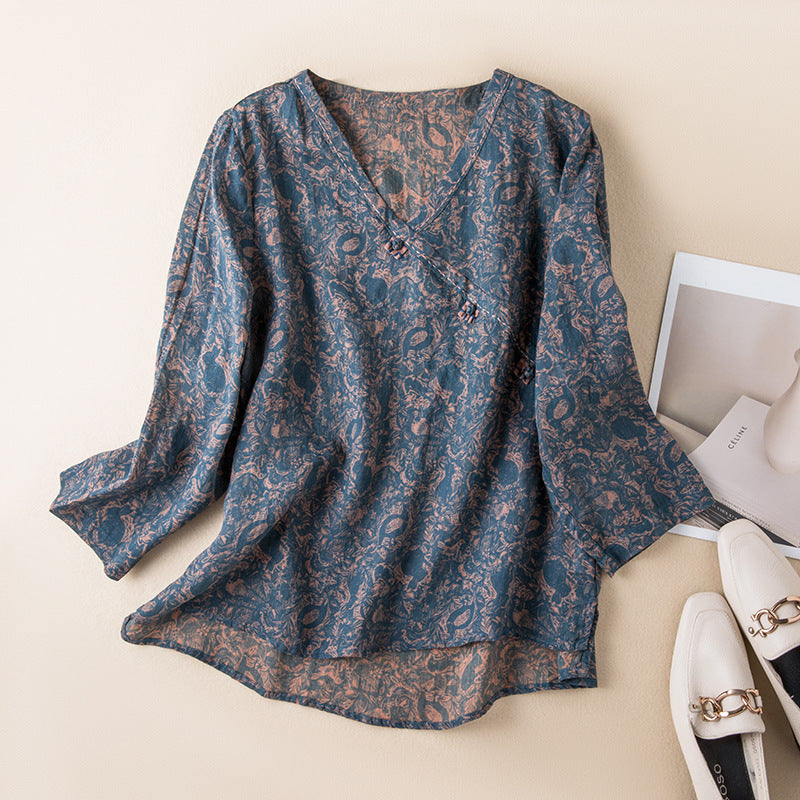 Flat lay of a dark blue women's V-neck shirt with a brown floral print and three-quarter sleeves