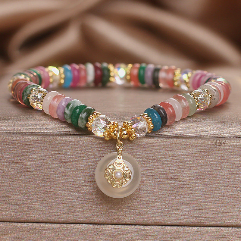 Close-up of a colorful crystal bracelet with a white peace buckle charm