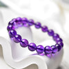 Round purple faux crystal beads on a white curved surface