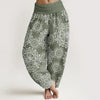 Woman wearing green printed high-waist harem pants standing against a white background