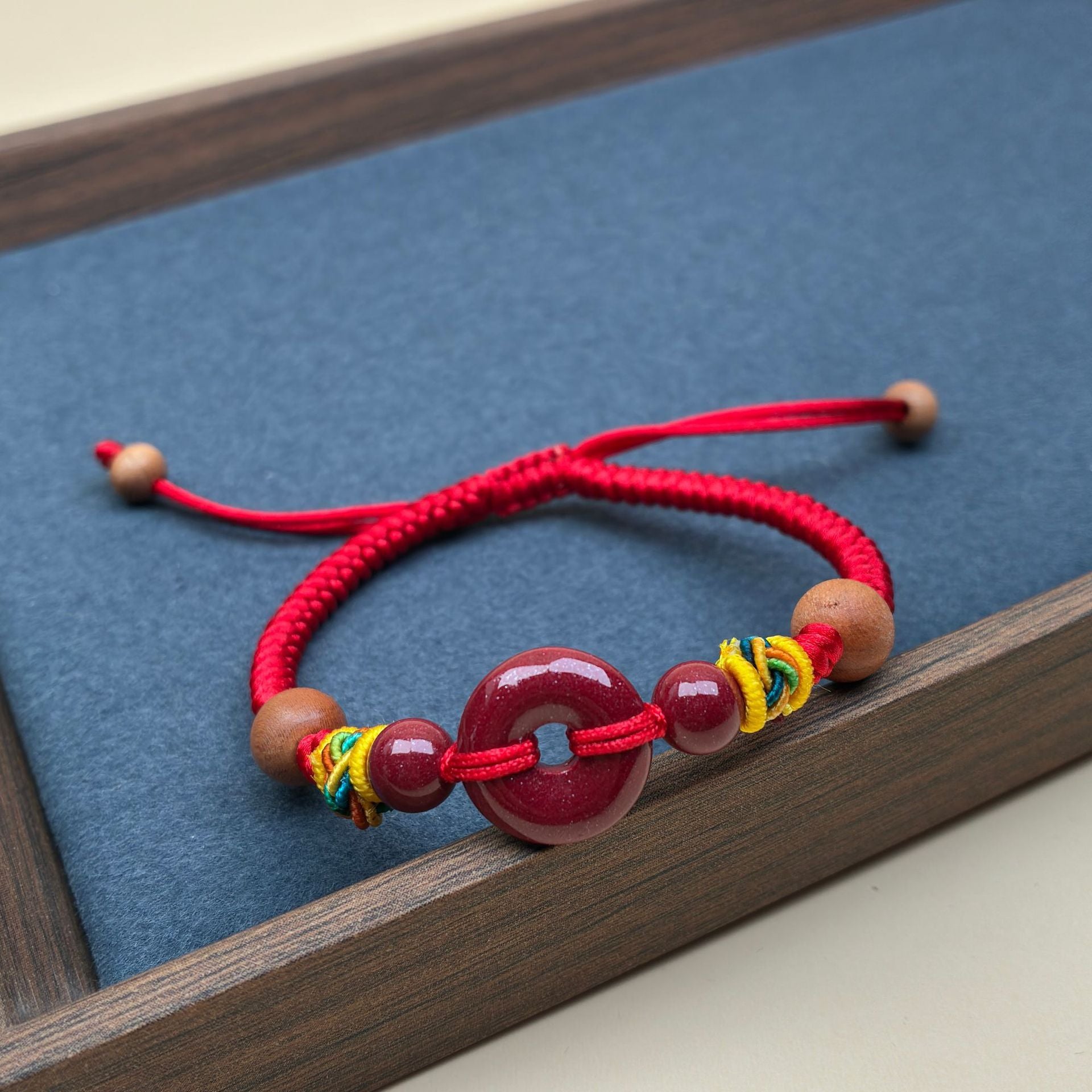 Close up of a red string bracelet with a red peace buckle charm on a wrist