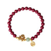 Close-up of a red cinnabar beaded bracelet with a jade bead and gold horse charm