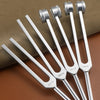 Four silver aluminum alloy tuning forks laid out on a brown surface