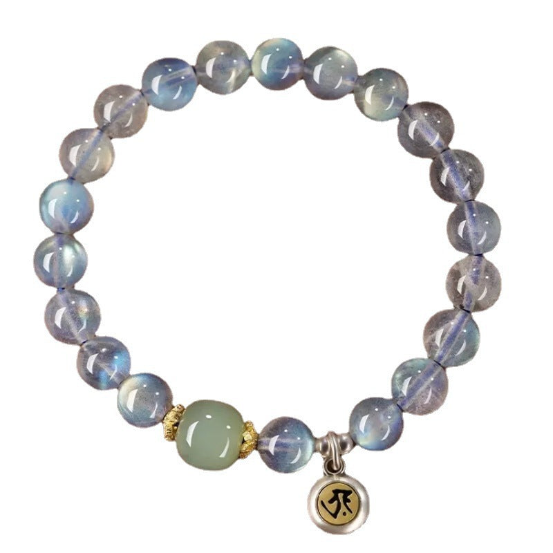 Natural grey moonstone beaded bracelet with a gold-tone charm on a wooden surface