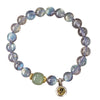 Natural grey moonstone beaded bracelet with a gold-tone charm on a wooden surface