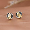 Close up of round sterling silver stud earrings with gold prayer hands
