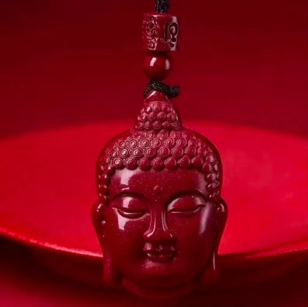 Close-up of a red cinnabar pendant carved in the shape of a Buddha head on a black cord
