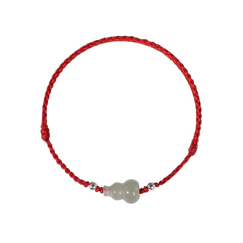 Close up of a red braided bracelet with a white jade gourd charm