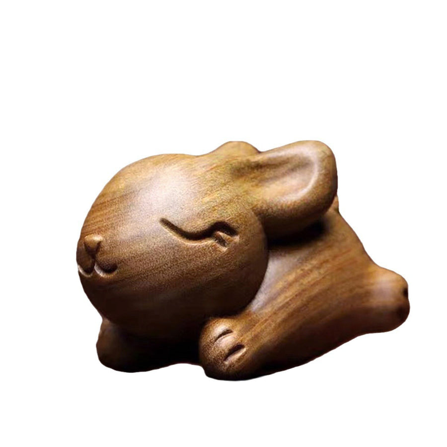Small carved green sandalwood rabbit figurine sitting on a white background
