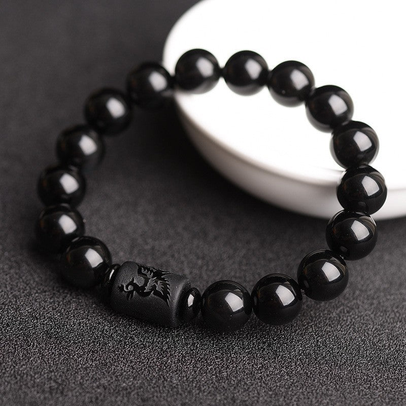 Close up of black obsidian bracelet with carved dragon detail
