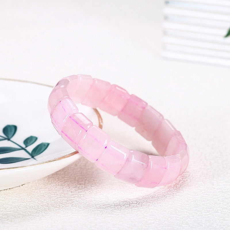 Pink rose quartz paddle bead bracelet resting on a white dish