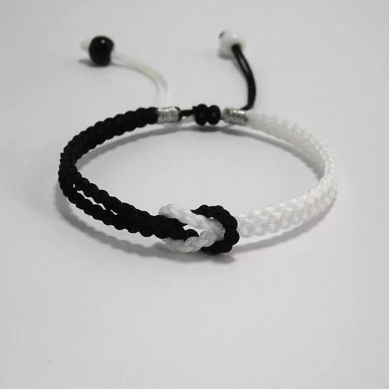 Close-up of a black and white braided cord bracelet with an adjustable sliding knot closure
