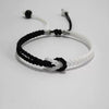 Close-up of a black and white braided cord bracelet with an adjustable sliding knot closure