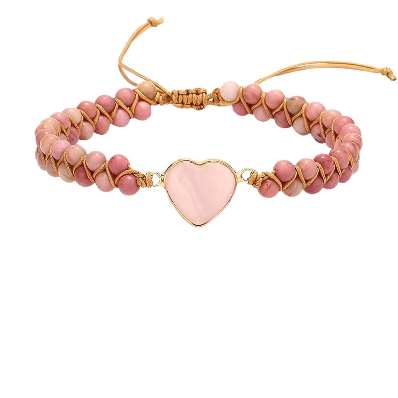 Pink rhodochrosite beaded bracelet with a heart charm on wood