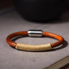 Close-up of a red braided leather bracelet on a wrist resting on a wooden table