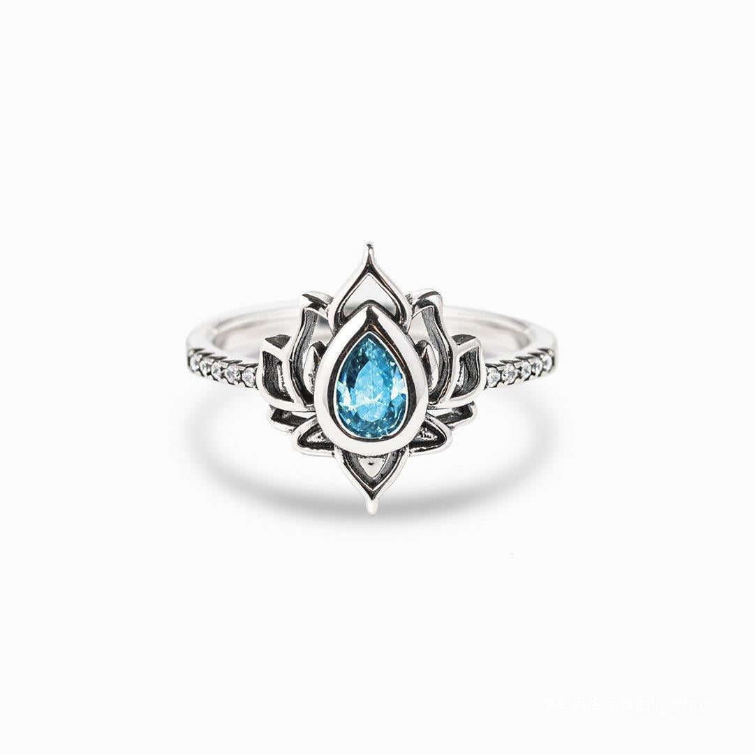 Silver tone ring with a blue teardrop stone inside a lotus flower design