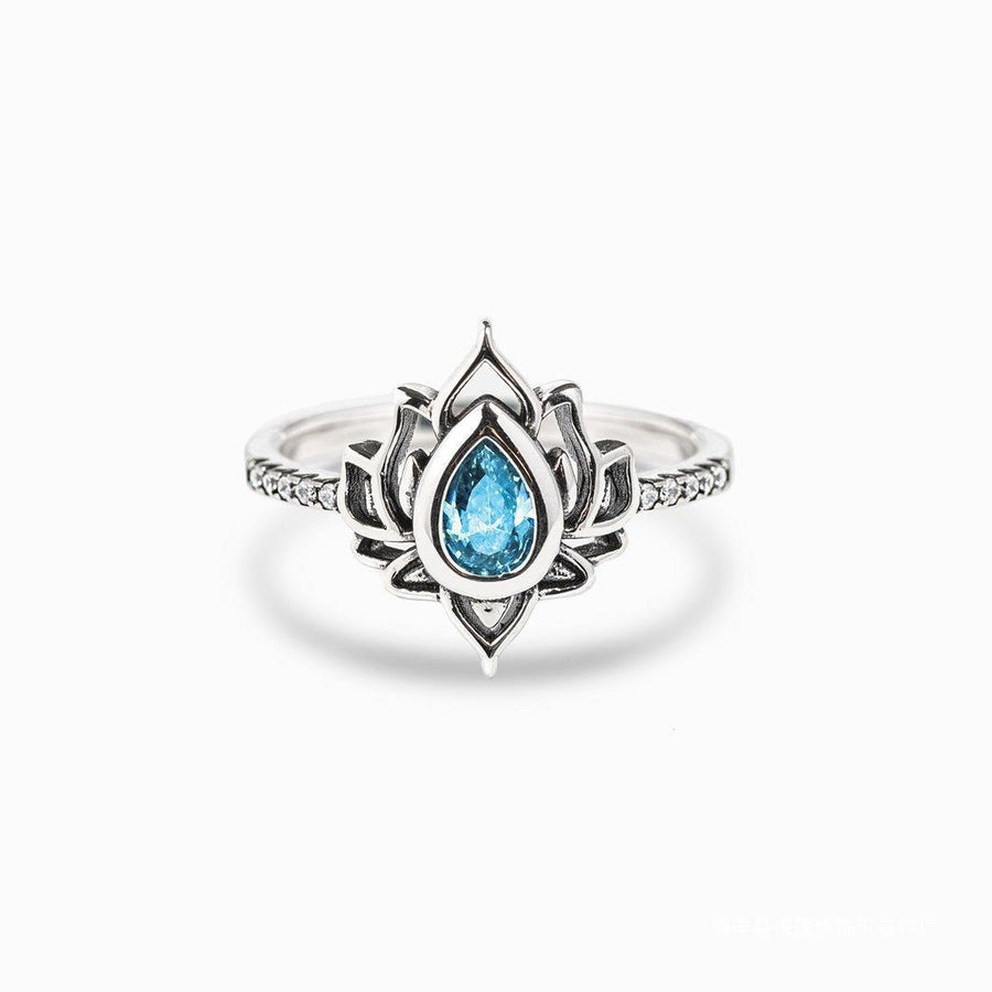 Silver tone ring with a blue teardrop stone inside a lotus flower design