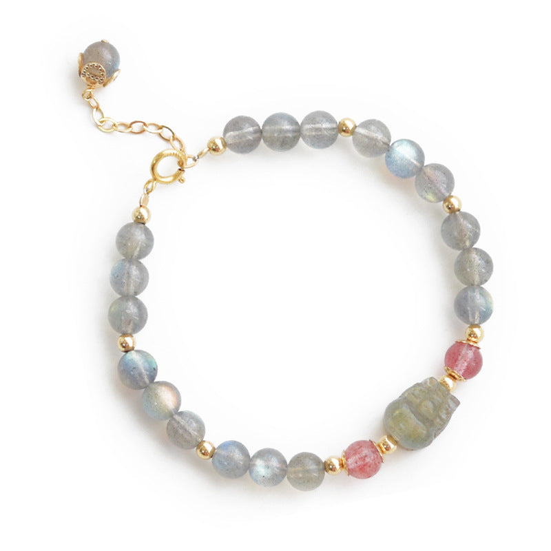 Close-up of a beaded bracelet with grey moonstone, pink stones and a central carved charm on a wrist