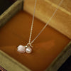 Gold-tone necklace with a white shell pendant and a round pearl resting in a jewelry box