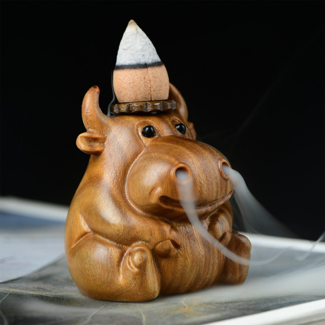 Close up of a wooden calf shaped incense burner with smoke flowing from its nostrils