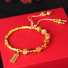 Gold-tone beaded bracelet with an abacus charm on a red background