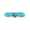 Close up of a blue turquoise beaded bracelet with a sea turtle charm on a white background