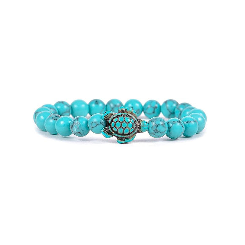 Close up of a blue turquoise beaded bracelet with a sea turtle charm on a white background
