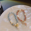 Two beaded bracelets with pearl accents and charms resting on a white plate