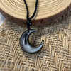 Close up of a silver sheen obsidian crescent moon pendant on a black cord