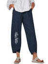 Model wearing loose fit dark blue linen pants with a white leaf print on the leg