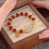 A beaded bracelet with a white rabbit charm and gold spacers resting in a wooden box.