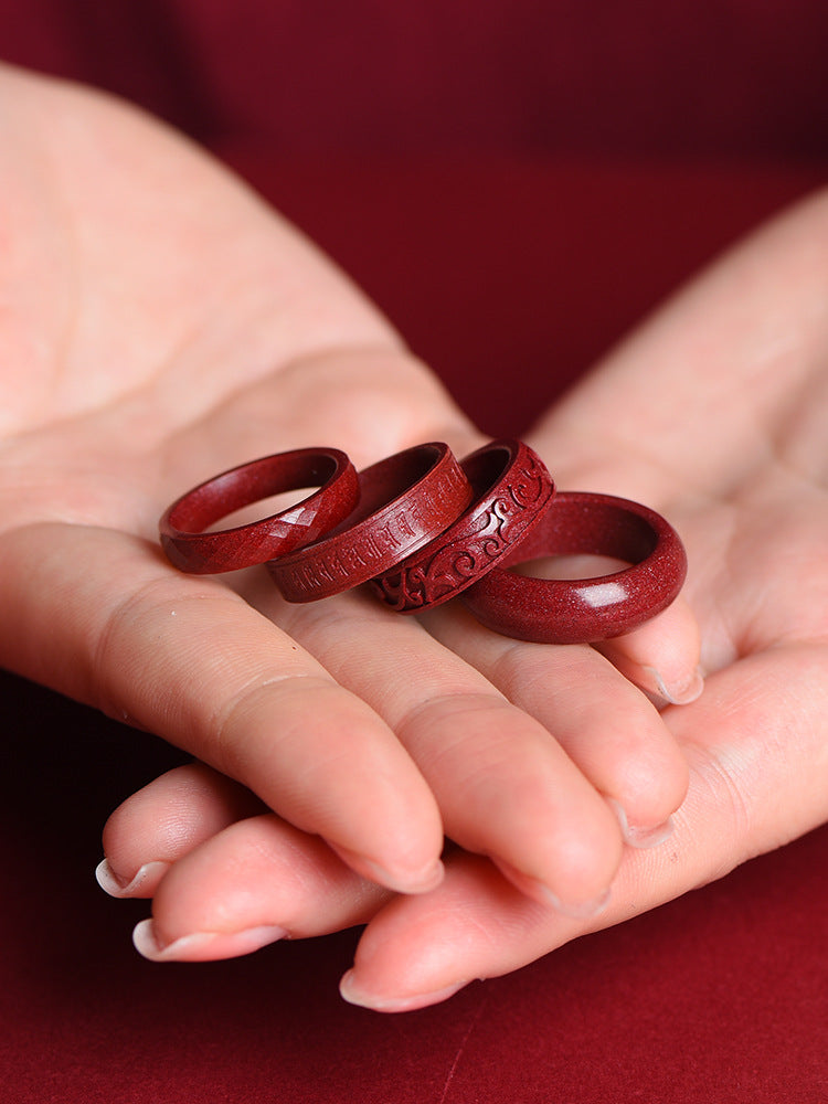 Red cinnabar rings held in hands showing smooth and carved designs