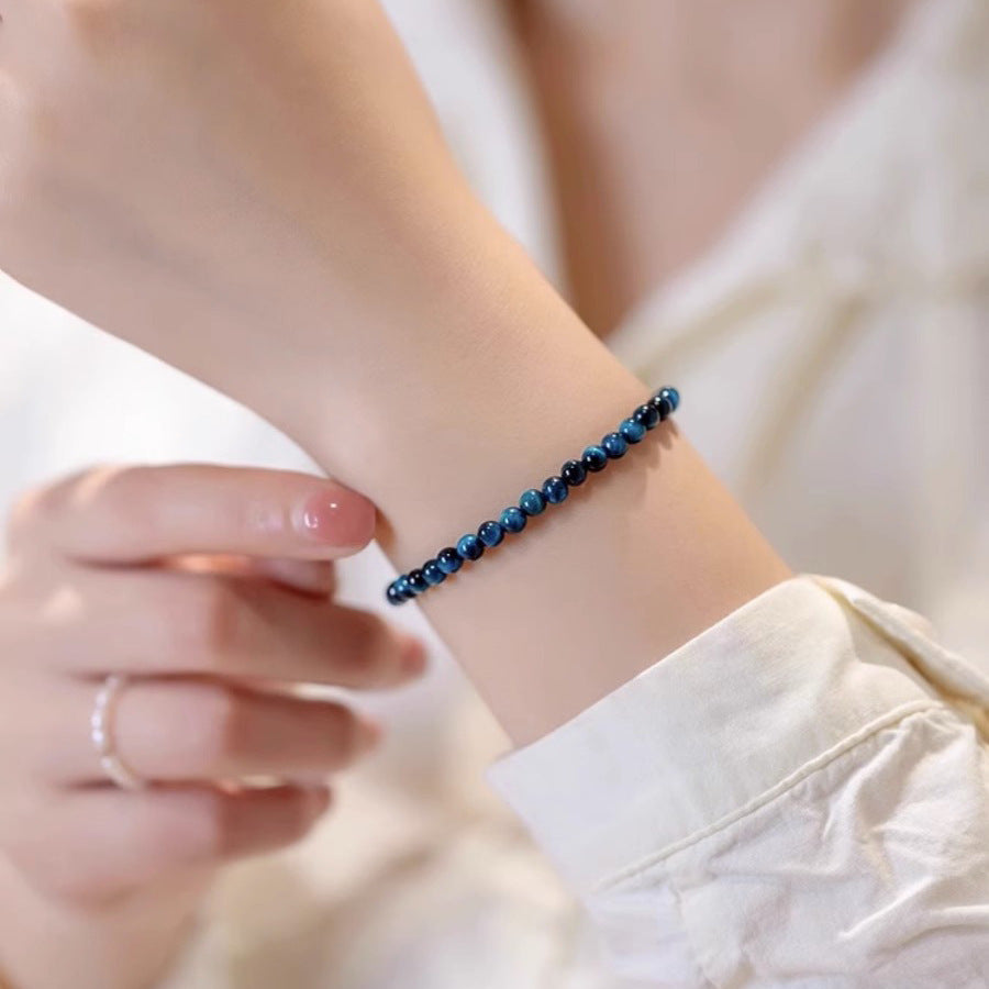 Close up of a blue tiger eye stone bracelet on a woman's wrist
