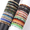Stack of colorful 4mm stone mini bead bracelets on black and white display stands