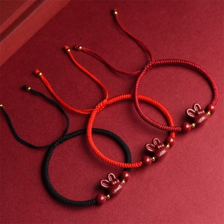 Three hand-braided bracelets with cinnabar rabbit charms in red and black cords