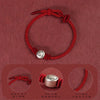 Close-up of a red braided cord bracelet with a silver bead showing a cartoon horse face