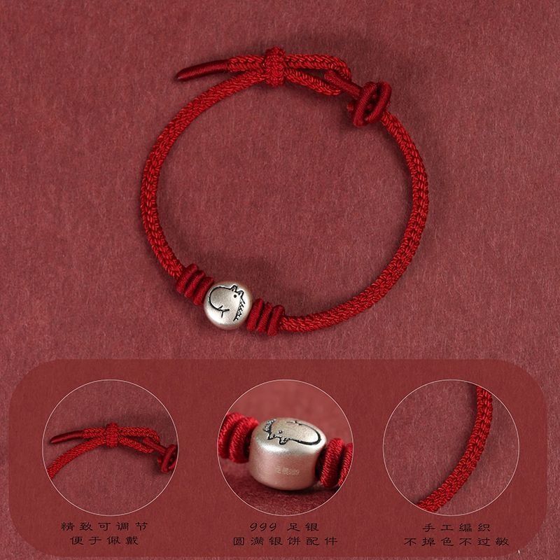 Close-up of a red braided cord bracelet with a silver bead showing a cartoon horse face