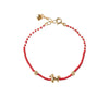 Close up of a red beaded bracelet with a small gold horse charm on a white background