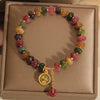 Colorful tourmaline beaded bracelet with a gold rabbit charm resting on a box