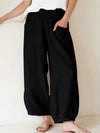 Model wearing black wide-leg cropped harem pants with hands in pockets