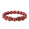Close up of a red cinnabar bracelet with two carved mythical creatures