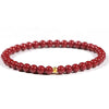 A close up of a red cinnabar beaded bracelet worn on a wrist